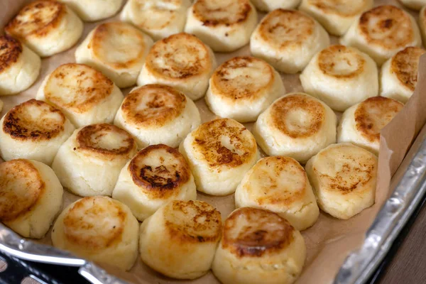 Pişirme tepsisinde cheesecake, yemek odasında aşçı. Güzel, pembe ve kızarmış.