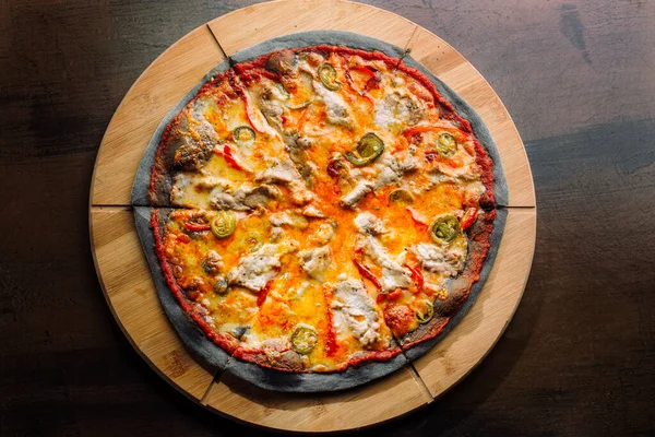 Pizza med jalapeno peppar, torkade tomater och kycklingbröst på svart deg. — Stockfoto