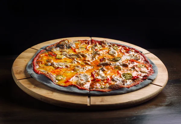 Pizza med jalapeno peppar, torkade tomater och kycklingbröst på svart deg. — Stockfoto