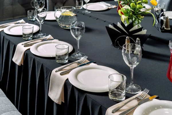 Сервировка стола для свадьбы или ужина, черная скатерть, белые тарелки. — стоковое фото