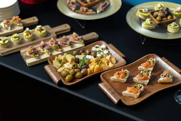 Gourmet appetizers: salmon, prosciutto, olives. Snacks are laid out on wooden boards. Luxury catering. side view. — Stock Photo, Image