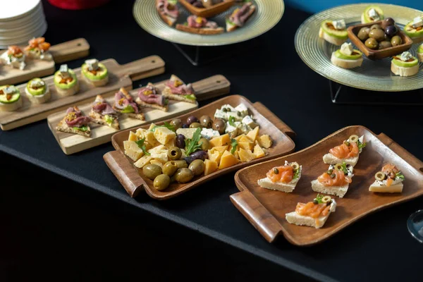 Aperitivos gourmet: salmão, prosciutto, azeitonas. Os lanches são colocados em tábuas de madeira. Um restaurante de luxo. vista lateral. — Fotografia de Stock