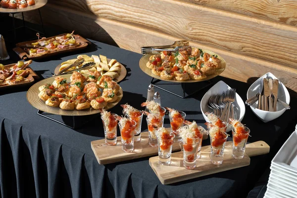 Yemek servisi. Peynirle doldurulmuş profiteroller. Fincanda karides, buğday ipliğinde karides. Güzel bir masa, güneş ışığı. Lüks yemek servisi.