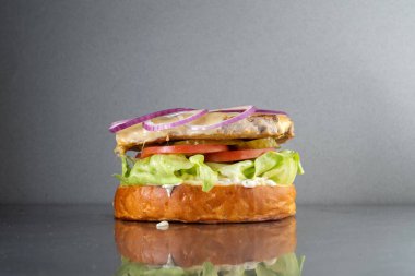 Gri metal bir masada soğanlı ve mayonezli hamburger. Abur cubur, lezzetli..