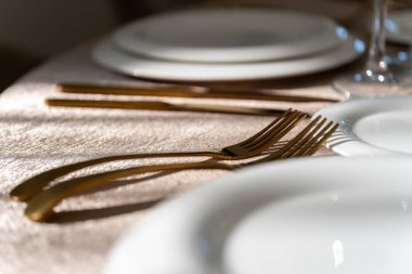 Şık ve zarif, altın kaplama çatal bıçak takımı ve beyaz tabaklar, boş tabaklar. Lüks restoran, kutlama hazırlığı. Makro.
