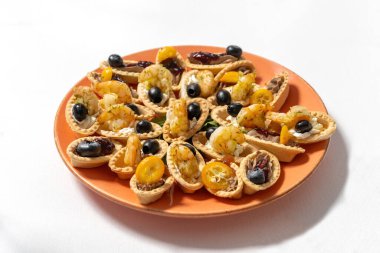 Krem peynirli tart, karides ve kumkuatla süslenmiş siyah zeytin..