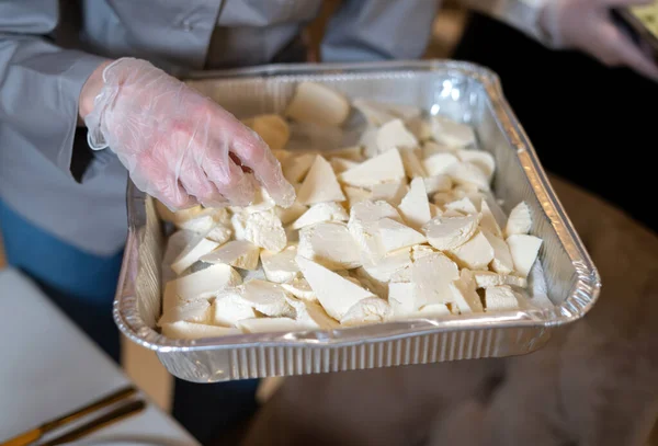 Δίσκος αλουμινίου στα χέρια ενός μάγειρα με φέτες τυριού. — Φωτογραφία Αρχείου