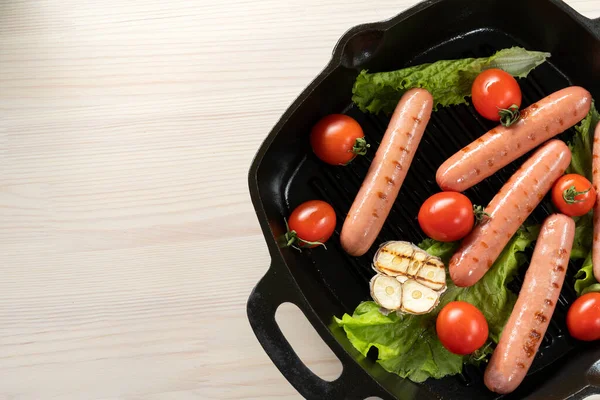 Uzenky v litinové pánvi, s rajčaty, salátem, smaženým česnekem-2. — Stock fotografie