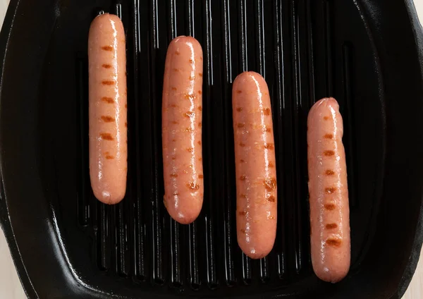 Saucisses frites sur une poêle en fonte, vue sur le dessus. — Photo