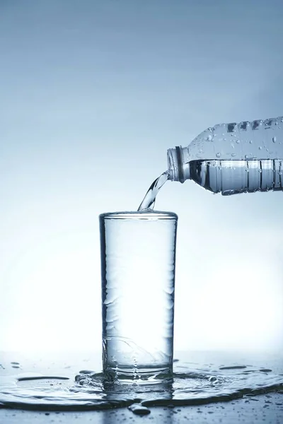 Image of pouring water from a water bottle into a glass until it\'s full.
