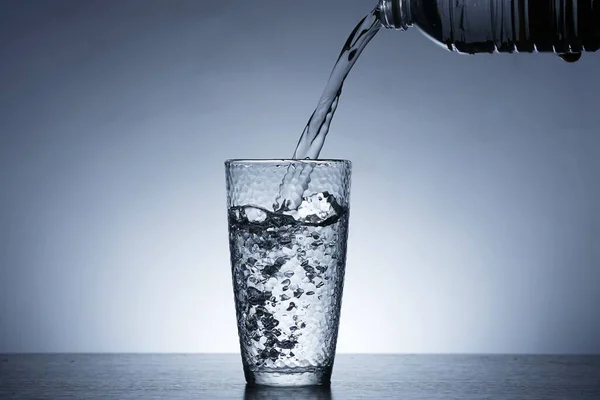 Photo of pouring water into a glass of water