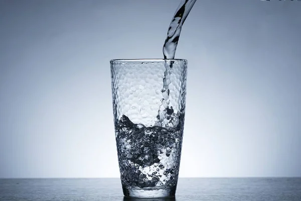 Photo of pouring water into a glass of water