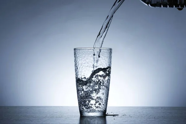 Photo of pouring water into a glass of water