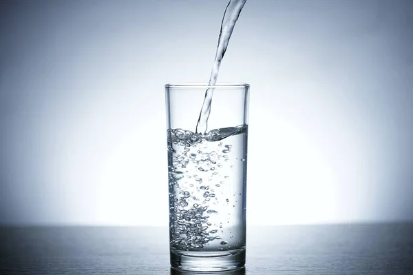 Photo of pouring water into a glass of water