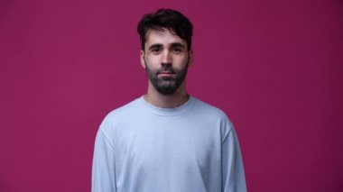 Bir adama gülüyor, kameraya gülüyor, çok komik, arka plan pembe, mavi bir bluz giyiyor.