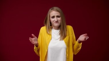 Kız bu konuda hiçbir şey göstermiyor, ellerini kaldırdı ve hayır gösteriyor, beyaz tişört ve sarı gömlek giymiş, arka plan kırmızı.