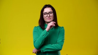 Kadın ne yapacağını bilmiyordu ve aniden bir fikir geldi, gülümsedi, esmer, gözlük takıyor, yeşil gömlek giyiyor, arka plan sarı.