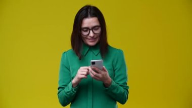 Bir kadın telefonunda piyangoyu kazandığına dair bir tebligat aldı, çok mutluydu, bağırdı, esmer, kısa saçlı, gözlük takıyor, yeşil gömlek giyiyor.