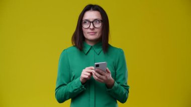 Esmer, telefonda SMS yazar, düşünceli bir şekilde gülümser, kısa süre sonra yıkanır, gözlük takar, yeşil bir gömlek giyer, arka plan sarıdır.