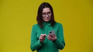 Kadın bir telefon aldı ve hoş olmayan bir haber aldı, çok pasif ve sinirli bir hale geldi, hayır dedi, esmer, kısa saçlı, gözlüklü, yeşil gömlek giyiyor, arka planı sarı