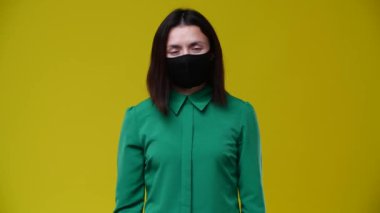 Esmer kadın maskesini çıkardığında, hemen gülümsedi, kısa saç kesimi vardı, yeşil tişört giymişti, arka plan sarıydı.
