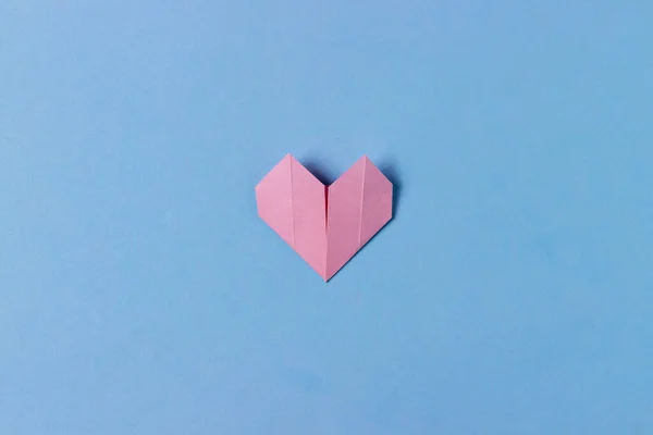 用折纸技术在蓝色背景上折叠粉红纸的心 爱的概念 最低限度的背景 — 图库照片