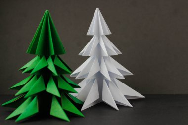 Siyah arka planda iki origami yeşil ve beyaz noel ağacı. Beyaz bir ağaca odaklan.