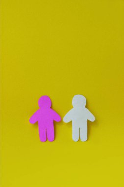 Beyaz ve pembe kağıtlardan oyulmuş iki insan silueti. İletişim kavramı, ilişkiler, aşk, takım çalışması. Dikey fotoğraf