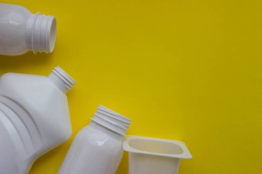 Sarı arka planda beyaz plastik şişeler ve senin tasarımın için yer var. Üst görünüm