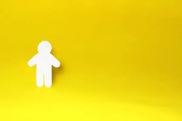 白い紙の男のシルエット 手でカット 黄色の背景に写真の左側にあります 社会の概念 — ストック写真