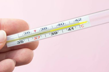 Pembe arka planda civa termometresi var. Fotoğrafı kapat. Termometre 38.7 santigrat derece gösteriyor.