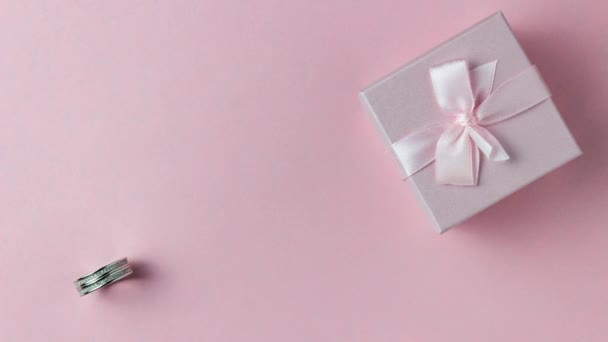 Серебряное кольцо в розовой подарочной коробке на розовом фоне. Милый стоп-ролик. Обручальное кольцо — стоковое видео
