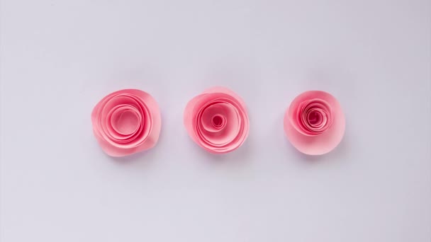 Три розовых позы постепенно появляются на светлом фоне. Бумажные цветы Оригами. Остановите видео движения. Концепция загрузки, ожидания — стоковое видео
