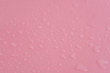 Su damlacıkları güzel pembe bir zemin üzerinde