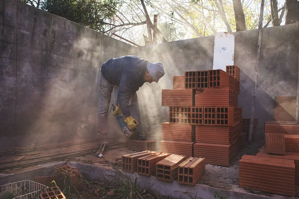 Mason cutting brick with the grinder between sunbeams. High quality photo