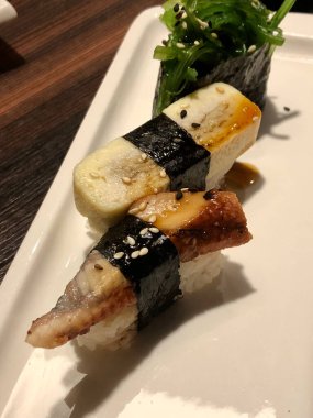 Beyaz bir tabakta üç Japon suşisi.