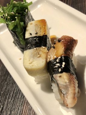 Üç Japon suşi yılanbalığı, yumurtalı omlet ve yakın plan chuka salatası.