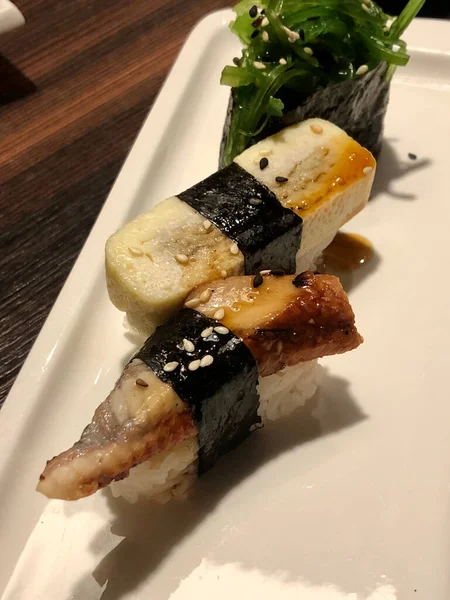 Beyaz bir tabakta üç Japon suşisi.