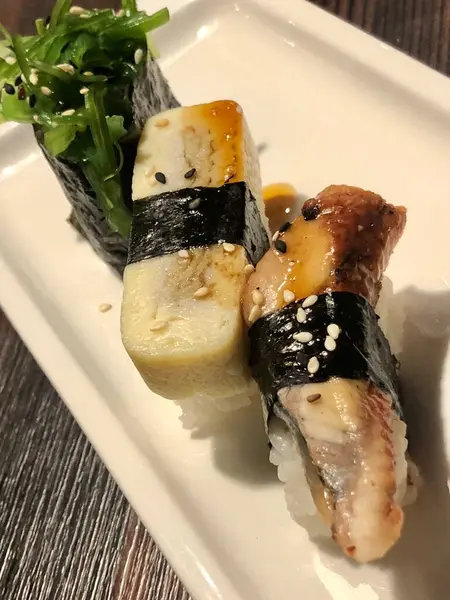 Üç Japon suşi yılanbalığı, yumurtalı omlet ve yakın plan chuka salatası.