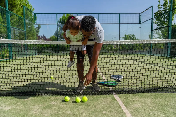 Black father and daughter on tennis court