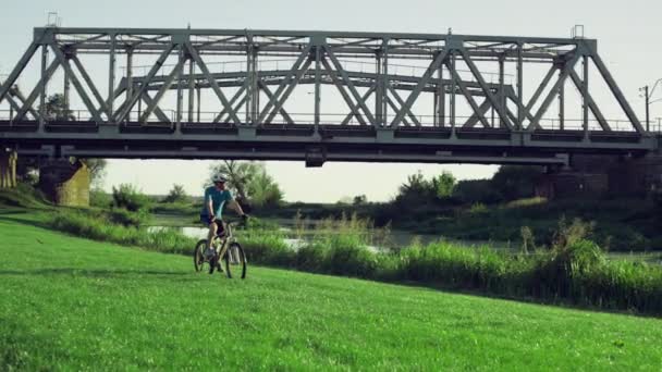 Le gars fait du vélo sur l'herbe dans un beau paysage — Video