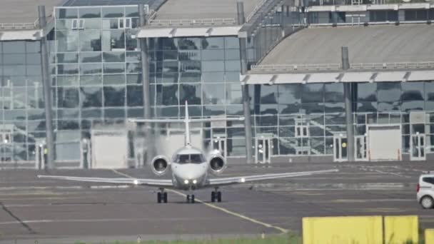 A small plane rides in the background of the airport building. — Stock Video