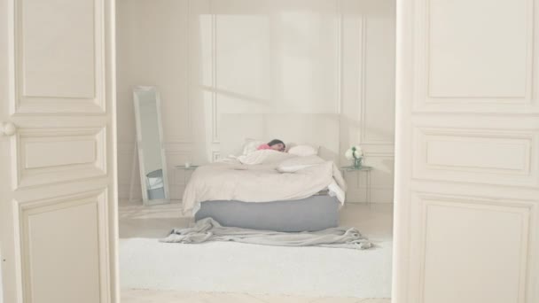 Mattina nella camera da letto dove la ragazza si è svegliata. Una ragazza caucasica si alza dal letto. — Video Stock