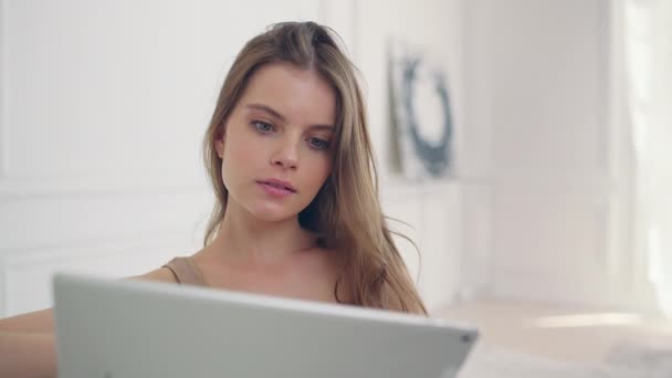 Fiatal lány egy gyönyörű belső a nappaliban néz a tabletta — Stock videók