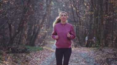 Sonbahar ormanlarında koşan bir kadının yavaş çekim videosu..