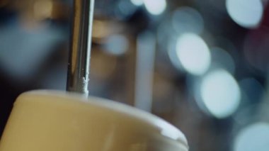 Bardaki barmen bardağa bira doldurur..