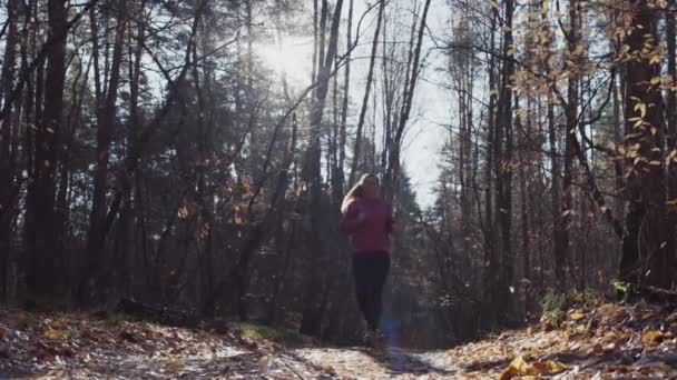 Fehér nő fut keresztül az erdőn a fák között. — Stock videók