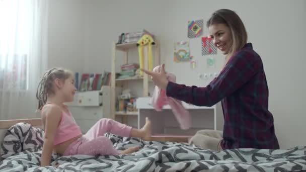 Mamma mette sua figlia in un maglione sul letto. — Video Stock