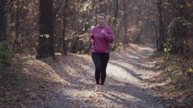 Beyaz kadın ağaçlarda sarı yapraklarla sonbahar ormanlarında koşuyor..