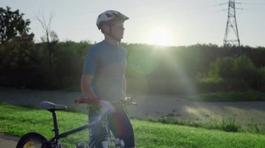 Bisikletli adam parkta bisikletle yürüyor. Etkin bisikletten sonra yürü.